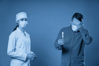 年轻的医生测量温度病人温度计工作室拍摄蓝色的背景
