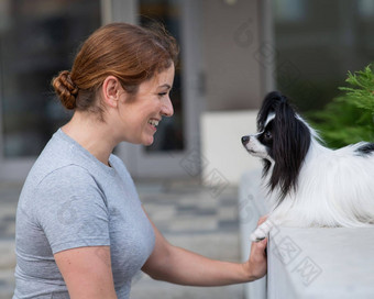 高加索人红发女人拥抱帕皮<strong>利</strong>翁狗在户外黑色的白色大陆猎犬