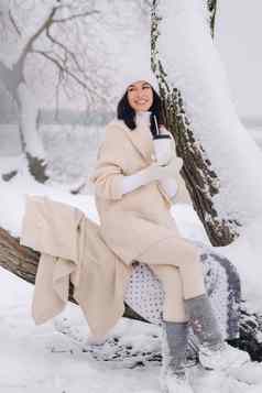 美丽的女孩米色开襟羊毛衫白色他享受喝茶雪冬天森林湖