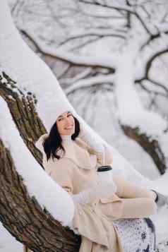 美丽的女孩米色开襟羊毛衫白色他享受喝茶雪冬天森林湖