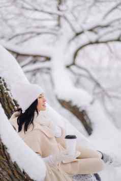 美丽的女孩米色开襟羊毛衫白色他享受喝茶雪冬天森林湖