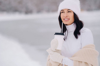 美丽的女孩米色开襟<strong>羊毛</strong>衫白色他玻璃茶享受雪路堤湖