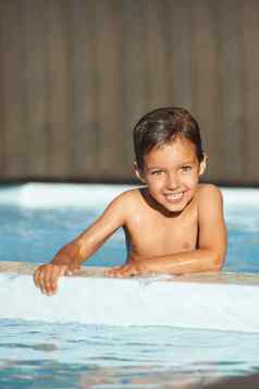 享受游泳肖像快乐年轻的男孩持有边缘游泳池