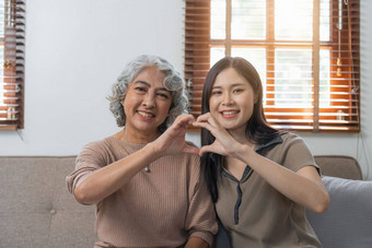 爱的成人女儿拥抱老妈妈。沙发上首页家庭享受温柔的时刻年轻的女人成熟的妈妈祖母一代又一代