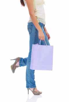 时尚的购物者裁剪视图年轻的女士腿持有购物袋