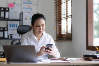 亚洲女商人移动PC<strong>电脑</strong>会说话的电话咨询客户<strong>端</strong>坐桌子上集中女销售经理使移动业务调用讨论工作客户办公室