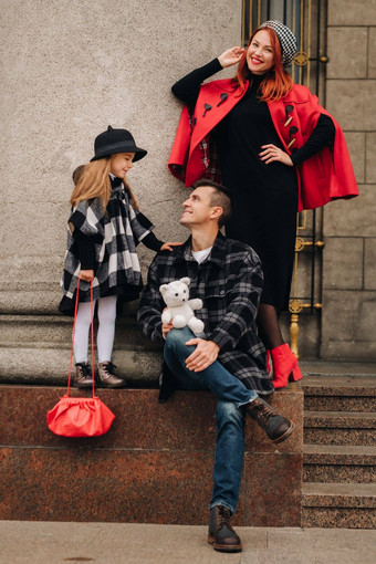 时尚的家庭漫步秋天城市摆姿势摄影师爸爸妈妈女儿秋天城市