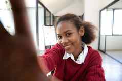 自拍照片智能手机快乐的无忧无虑的卷曲的非洲美国女孩学生自由职业者使自拍电话愚弄有趣的手机的网络摄像头微笑幸福的