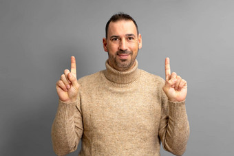 肖像有胡子的拉丁美洲人男人。<strong>高领</strong>毛衣毛衣快乐指出手指Copyspace孤立的灰色的背景