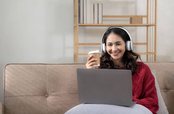 微笑年轻的女人耳机移动PC厅的女研究首页年轻的女人穿耳机听在线网络免费的音频首页