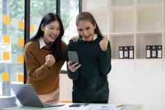 年轻的亚洲女商人显示快乐的表达式成功工作微笑幸福的移动PC电脑现代办公室