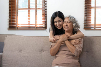 爱的成人女儿拥抱老妈妈。站沙发上首页家庭享受温柔的时刻年轻的女人成熟的妈妈祖母一代又一代
