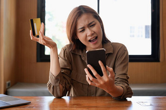 不开心年轻的亚洲女买家问题购买在线互联网智能手机信贷卡愤怒的沮丧女人困惑账户钱损失购物网络手机