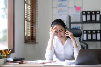 亚洲女商人移动PC电脑会说话的电话咨询客户端坐桌子上集中女销售经理使移动业务调用讨论工作客户办公室