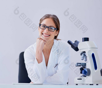 享受奖励职业生涯科学肖像微笑科学家坐着显微镜桌子上实验室