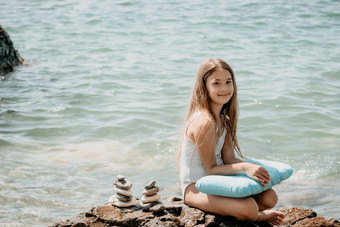 女人女儿图片石头金字塔海滨阳光明媚的一天蓝色的海背景快乐家庭假期卵石海滩平静海概念快乐假期海冥想水疗中心