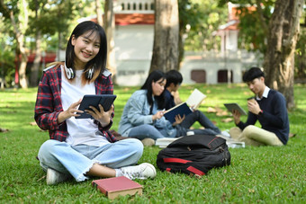 快乐的亚洲学生女人数字平板电脑绿色草地<strong>校园</strong>教育<strong>青年</strong>社区概念
