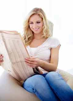 容易放松可爱的年轻的女人阅读报纸房子