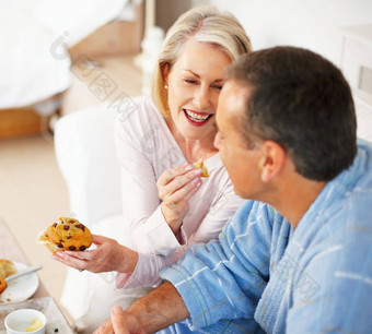 快乐的成熟的女人喂养松饼丈夫肖像快乐的成熟的女人喂养松饼丈夫