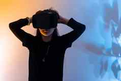 十几岁的女孩有趣的玩眼镜虚拟现实元宇宙玩游戏看电影听音乐购物色彩斑斓的霓虹灯未来主义的背景数字未来技术