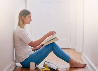 全神贯注<strong>叙述</strong>年轻的女人阅读书坐着地板上首页
