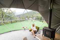 女人坐在地理圆顶豪华露营帐篷自然