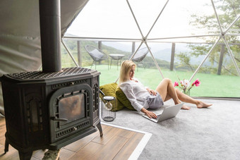 中间岁的女人移动PC休息支出时间豪华露营房子假期假期圆顶帐篷舒适的野营舒适生活方式概念