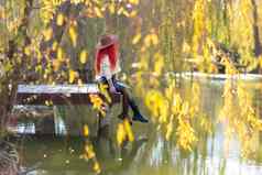 秋天湖女人坐在池塘木码头秋天欣赏自然概念旅游周末城市