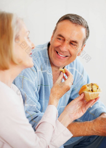 女人喂养松饼丈夫彩色的背景肖像爱的成熟的女人喂养松饼丈夫彩色的背景