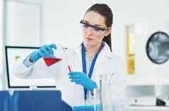 混合集中年轻的女科学家混合化学物质内部实验室一天