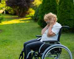 不开心上了年纪的女人哭坐着轮椅走在户外