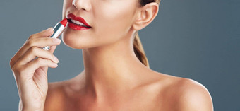 完美的阴影口红补充皮肤语气工作室拍摄美丽的年轻的女人把红色的口红灰色背景