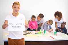 帮助手肖像志愿者持有志愿者需要标志志愿者工作孩子们背景