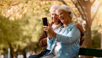 高级夫妇自拍微笑公园快乐树模糊背景社会媒体上了年纪的男人。女人智能手机公园板凳上幸福照片爱视频调用魁北克