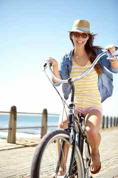 海边骑自行车美丽的年轻的女人骑自行车散步阳光明媚的下午
