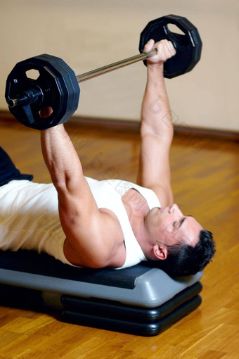 保持胸大肌完<strong>美</strong>的<strong>形</strong>状英俊的运动型男人。健身房练习