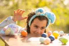 可爱的十几岁的女孩穿兔子耳朵持有复活节鸡蛋花园