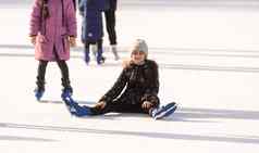 女孩下降了冰溜冰场冬天女孩坐在冰溜冰鞋秋天