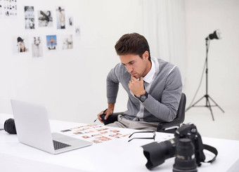 封面图像年轻的摄影师坐着桌子上编辑图片