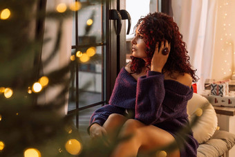 女人圣诞节窗口美丽的卷曲的女人紫色的毛衣坐着窗台上圣诞节树房间装饰圣诞节假期首页