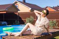 肖像漂亮的年轻的女人睡衣坐着充气游泳池夏天国家生活概念