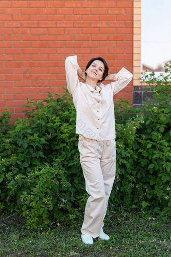 快乐的女人首页穿睡衣户外砖墙后院背景情绪睡衣裤家居服概念