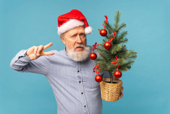 肖像快乐疯狂的情绪圣诞老人老人兴奋相机持有小圣诞节树蓝色的背景