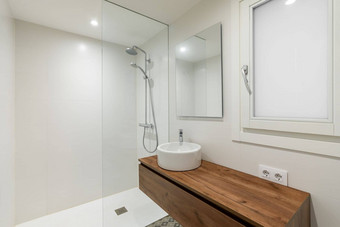 浴室小轮白色水槽长木工作台面浮动空气镜子水槽反映了墙相反窗口磨砂玻璃淋浴区域分离玻璃栏杆