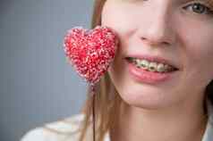 可爱的女人牙套牙齿持有糖果形式心白色背景