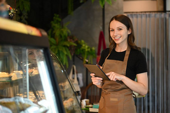 微笑高加索人女人小业务老板数字平板电脑站前面<strong>展示咖啡</strong>商店
