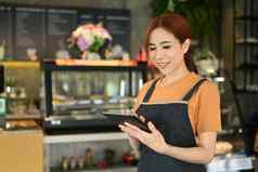 美丽的亚洲女人小业务老板数字平板电脑站咖啡馆室内创业开始业务概念