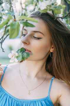 美丽的年轻的女孩蓝色的衣服盛开的苹果果园盛开的苹果树白色花