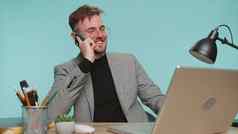快乐业务男人。老板享受移动电话调用会说话的的同事办公室工作空间桌子上