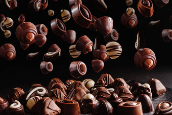 巧克力糖果馅料甜蜜的食物背景悬浮飞行甜蜜的棕色（的）巧克力蜜饯黑暗黑色的背景